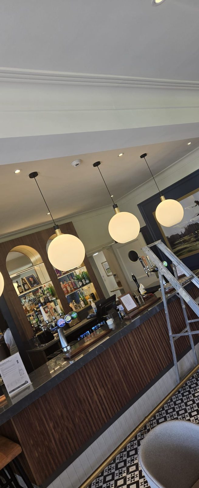 Bar counter lit by a row of glowing spherical pendant lights