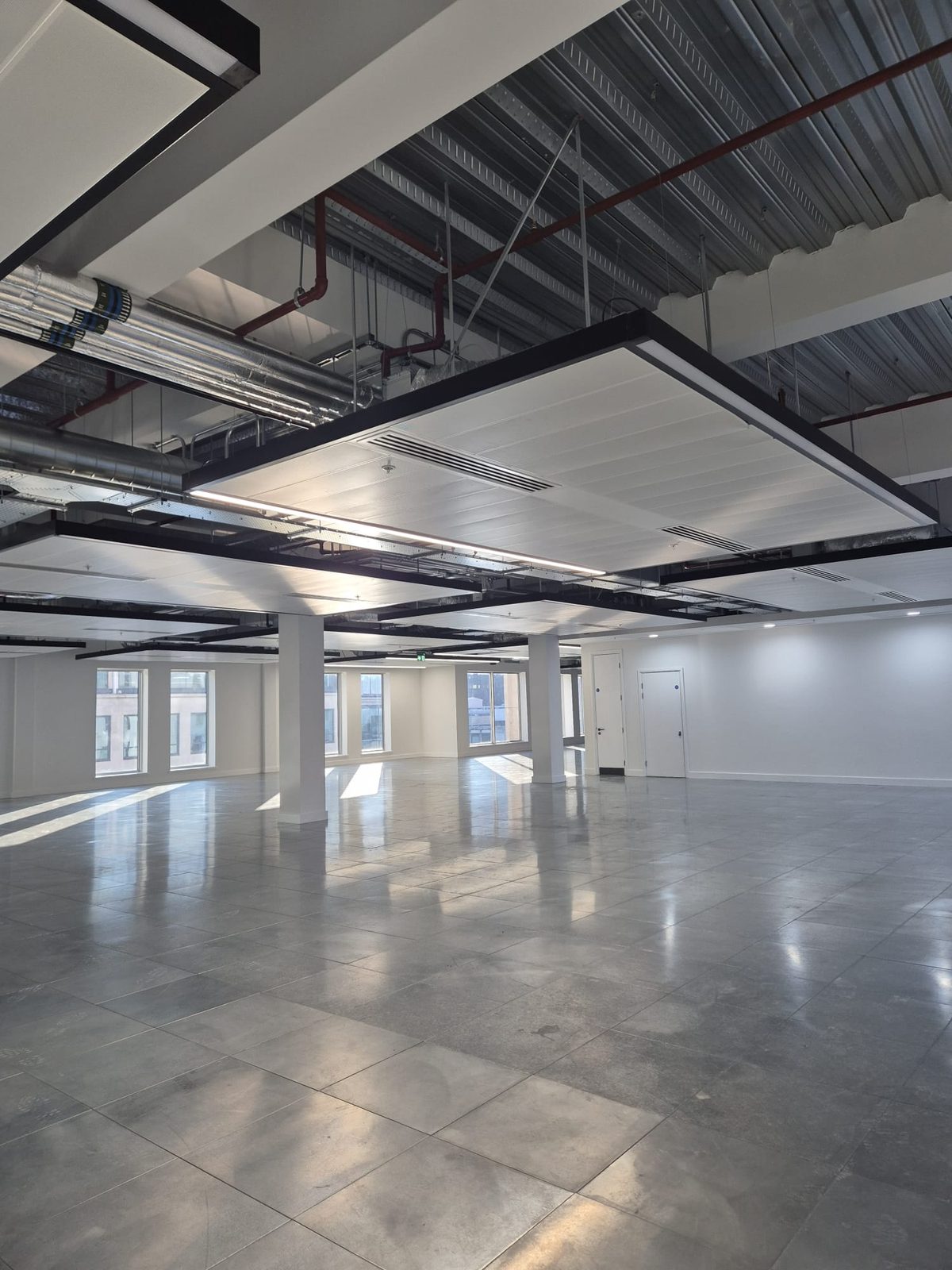 Large commercial interior at first fix stage with suspended ceiling grid and strip lighting