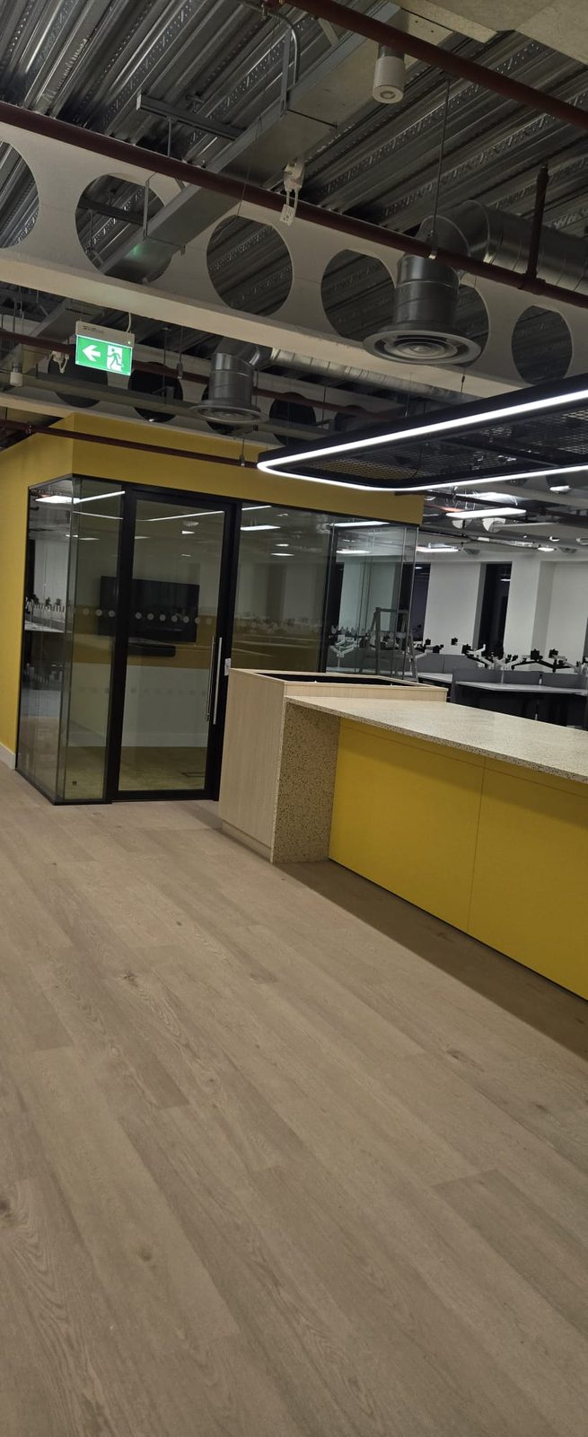 Office reception with a long glowing suspended linear light and exposed ducting